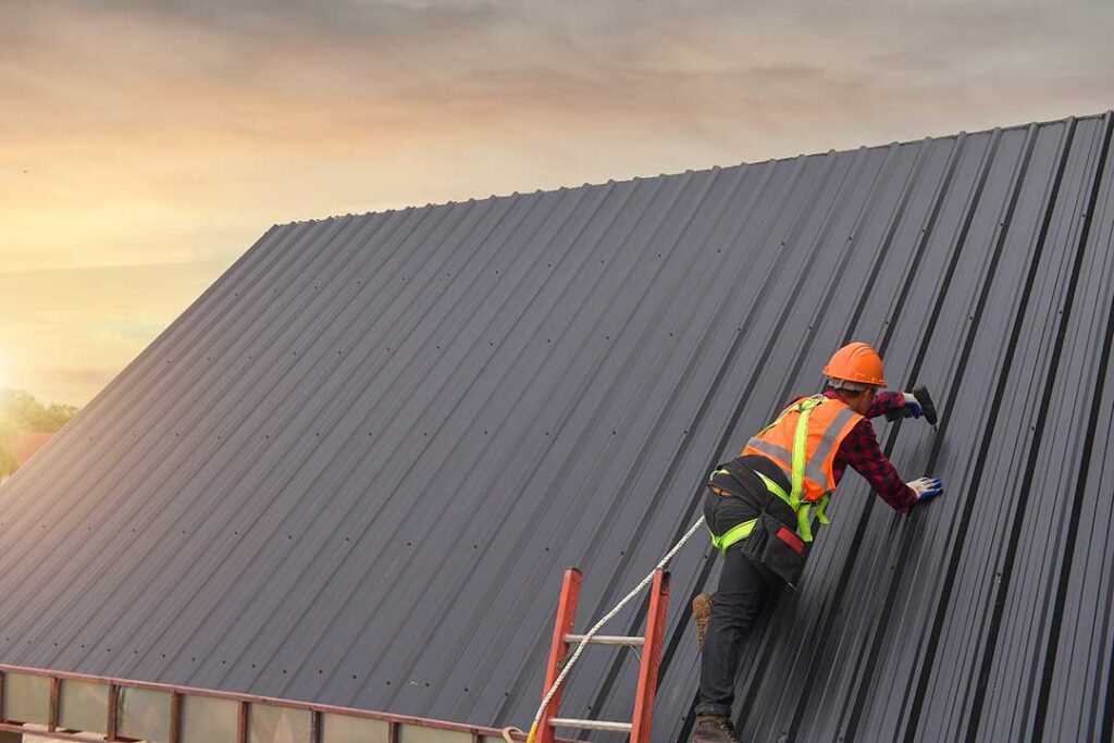Two homeowners examine roof shingles near a ladder on a suburban house after a winter storm.