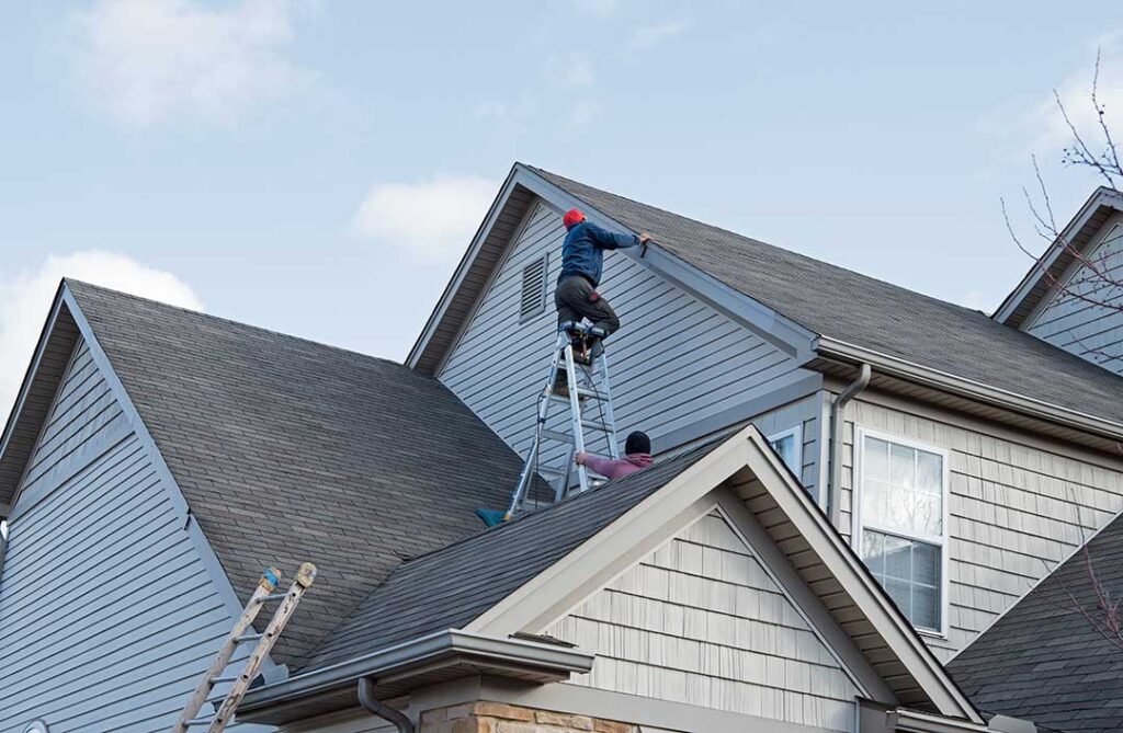 Metal flashing installed around a chimney and roof-to-wall junction on a shingled residential roof.
